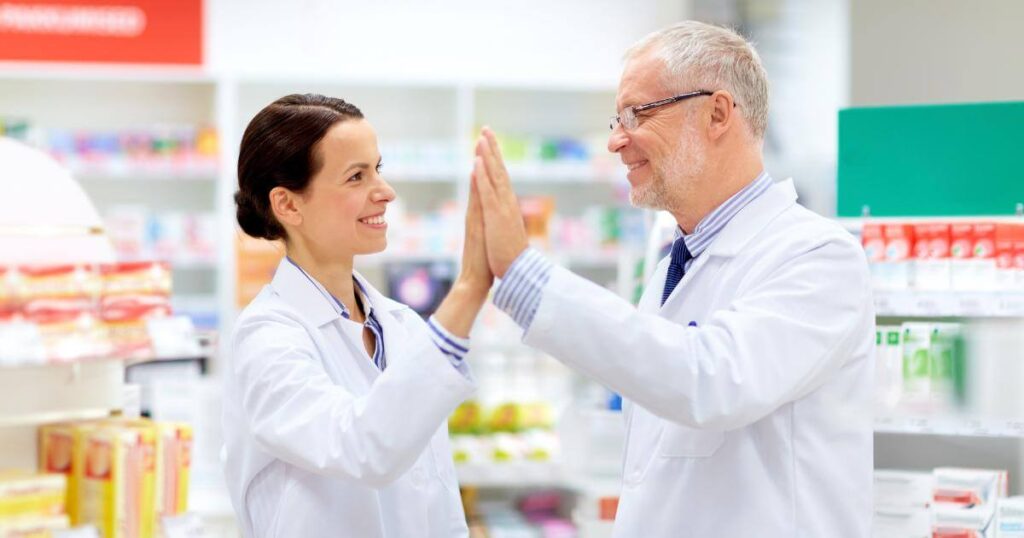 Two pharmacy staff members celebrating improved teamwork after resolving a workplace attitude issue
