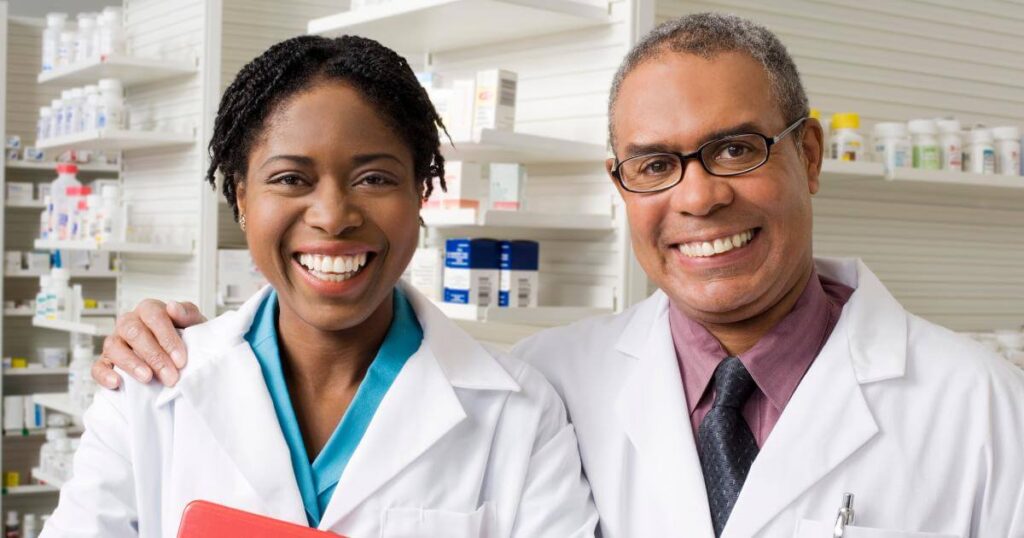 pharmacy director and manager smiling at camera with pharmacy in background