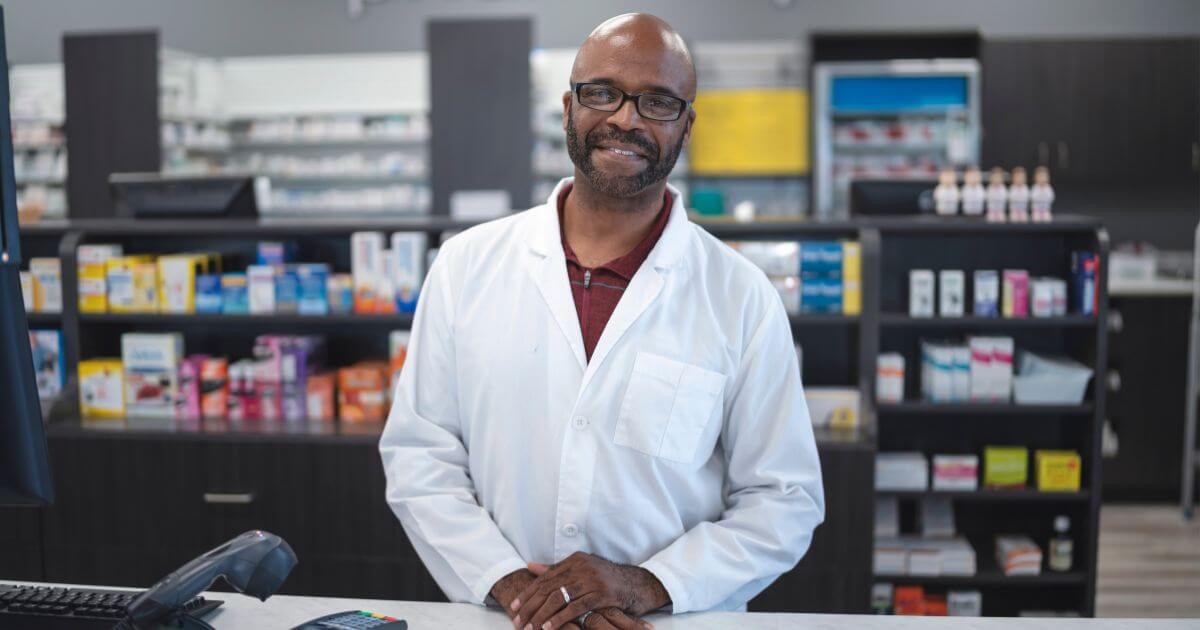 smiling male pharmacist standing in pharmacy
